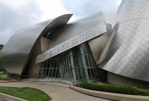 Modern architectural building with a unique, curved metallic facade and large glass entrance.