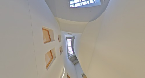 Abstract interior view of a curved white space with windows, creating a dynamic and modern architectural design.
