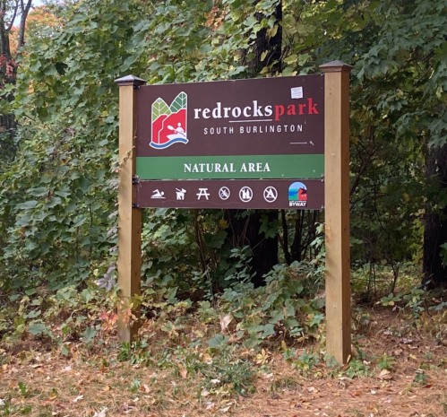 Sign for Red Rocks Park in South Burlington, indicating it is a natural area with various recreational activities.