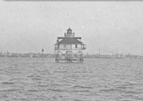 A vintage image of a lighthouse on stilts in the water, with a hazy shoreline in the background.