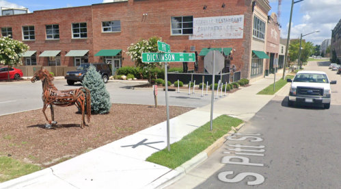 A street view showing a metal horse sculpture near a street sign for Dickinson Street and a parked white truck.