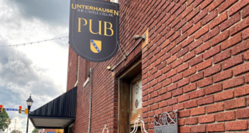 Sign for "Unterhausen Pub" on a brick wall, featuring a coat of arms and decorative elements.