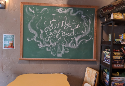 Chalkboard with the phrase "I solemnly swear I am up to no good" surrounded by whimsical illustrations.