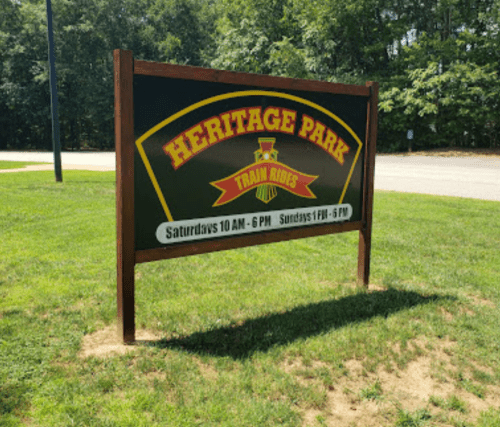 Sign for Heritage Park, featuring train rides, with hours: Saturdays 10 AM - 6 PM, Sundays 1 PM - 6 PM.
