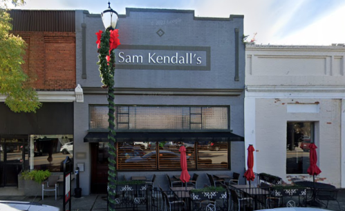 Exterior of Sam Kendall's restaurant, featuring outdoor seating and festive decorations on a sunny day.