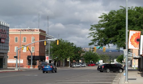 A quiet street scene with traffic lights, trees, and buildings, including a sign for "Newhouse" in the background.
