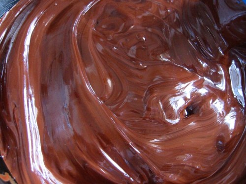 A close-up of smooth, glossy melted chocolate swirled in a bowl.