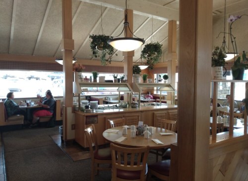 Interior of a casual dining restaurant with booths, a buffet area, and plants hanging from the ceiling.