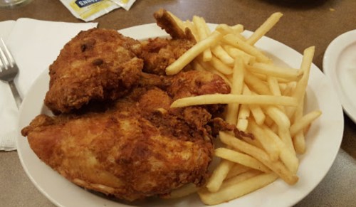 A plate of crispy fried chicken pieces served with a side of golden French fries.