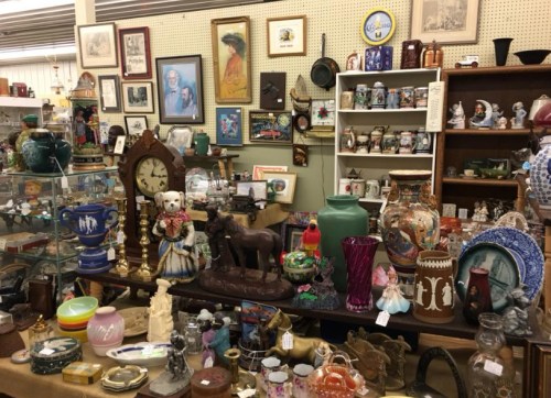 A cluttered antique shop filled with various collectibles, including clocks, figurines, and decorative items on display.