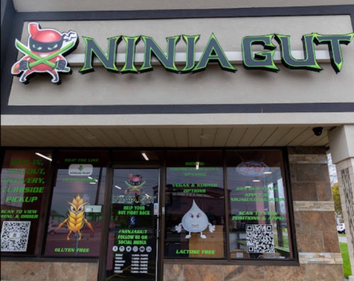Signage for "Ninja Gut" restaurant featuring a ninja logo, with details on menu options and dietary information.