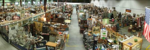 A wide view of a large antique store filled with various vintage items and furniture, with an American flag in the corner.