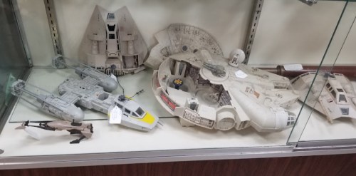 Display case featuring various model starships, including the Millennium Falcon and other sci-fi spacecraft.