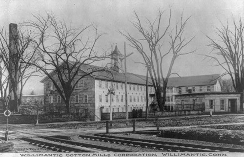Historic black-and-white photo of the Willimantic Cotton Mills Corporation in Willimantic, Connecticut, with bare trees.