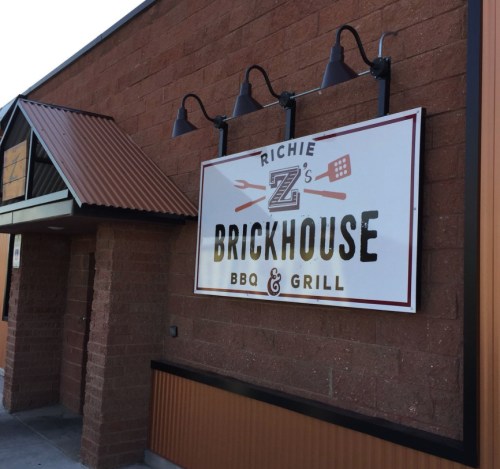 Sign for Richie Z's Brickhouse BBQ & Grill on a brick building with a metal roof.