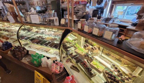 A display case filled with various chocolates and confections in a cozy shop setting.