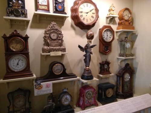 A collection of vintage clocks displayed on shelves, showcasing various styles and designs.