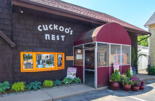 Exterior of Cuckoo's Nest restaurant featuring a screened entrance, colorful window, and potted plants.
