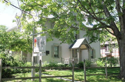 A white building with a sign reading "Stowe Center," surrounded by greenery and trees on a sunny day.