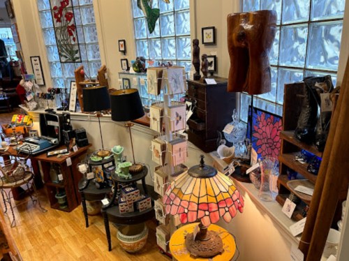 A cozy shop interior filled with various decorative items, lamps, and art pieces displayed on shelves and tables.