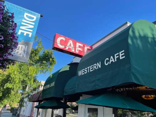 A café with green awnings and a red sign, surrounded by trees and banners that read "DINE" and "AUSTIN."