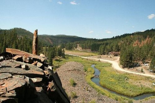 A scenic view of a winding river surrounded by lush greenery and hills under a clear blue sky.