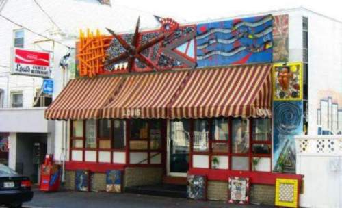 Colorful restaurant exterior with striped awning and vibrant murals on the walls.