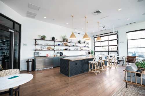 Modern kitchen and dining area with wooden floors, a large island, shelves, and stylish lighting fixtures.