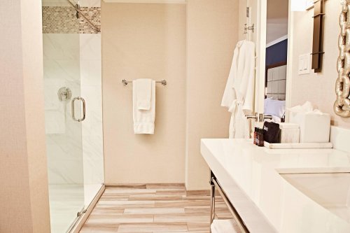 A modern bathroom featuring a glass shower, white towels, and a sleek vanity with toiletries.