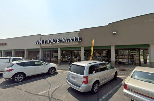 Exterior of an antique mall with several parked cars in front and a clear sky above.