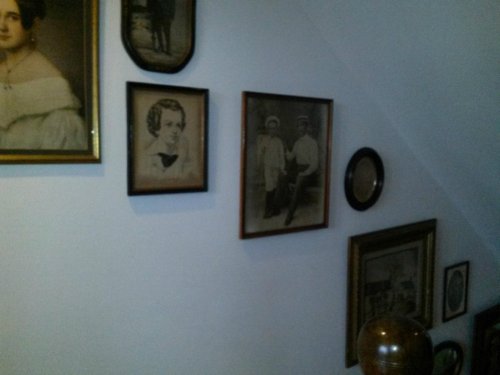 A wall adorned with various vintage framed portraits and photographs in different sizes and styles.