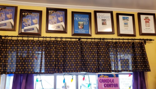 A wall display featuring framed awards and certificates above a patterned curtain in a cozy interior setting.