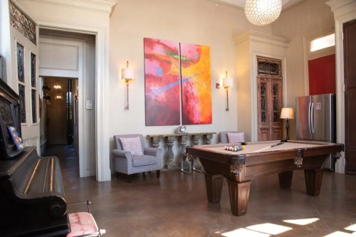 A stylish room featuring a pool table, modern art, and elegant seating, with warm lighting and a cozy atmosphere.