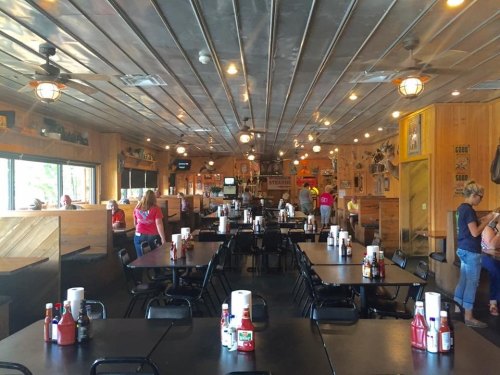 Interior of a casual restaurant with wooden decor, tables set for dining, and patrons enjoying their meals.