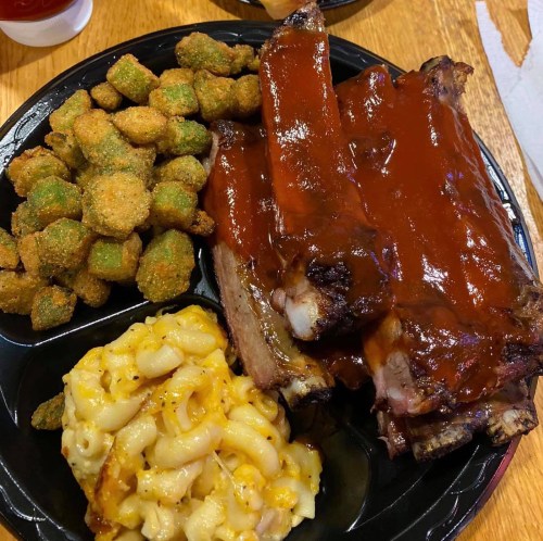 A plate of barbecue ribs with sauce, macaroni and cheese, and fried okra.