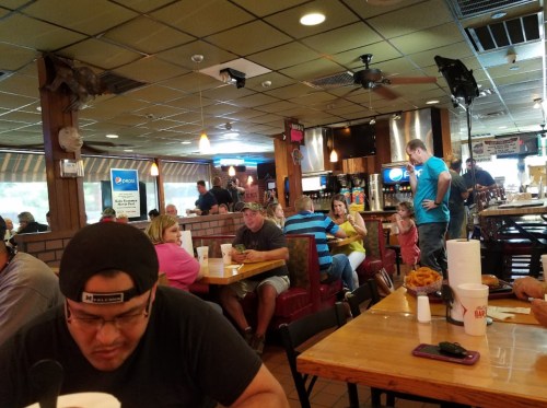 A busy restaurant interior with patrons seated at tables, enjoying meals and drinks in a casual atmosphere.