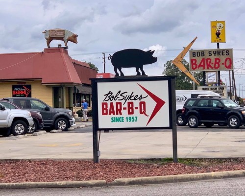 Sign for Bob Sykes Bar-B-Q featuring a pig silhouette on the roof, with a red arrow and "Since 1957" text.