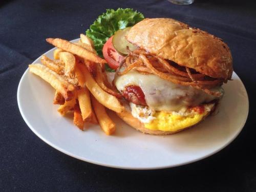 A juicy burger with melted cheese, lettuce, tomato, pickles, and crispy onions, served with golden fries on a plate.