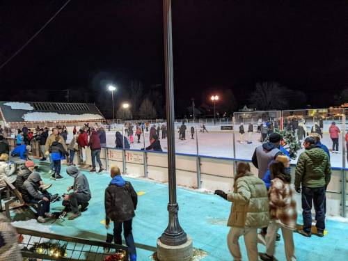 A bustling outdoor ice skating rink at night, with people skating and enjoying the winter atmosphere.