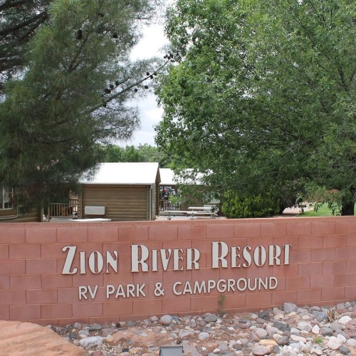 Sign for Zion River Resort RV Park & Campground, surrounded by trees and greenery.