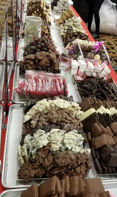 A colorful display of various chocolate treats and candies arranged on trays at a festive event.