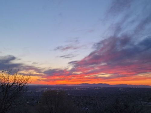 A vibrant sunset paints the sky with shades of orange, pink, and purple over a distant mountain range.