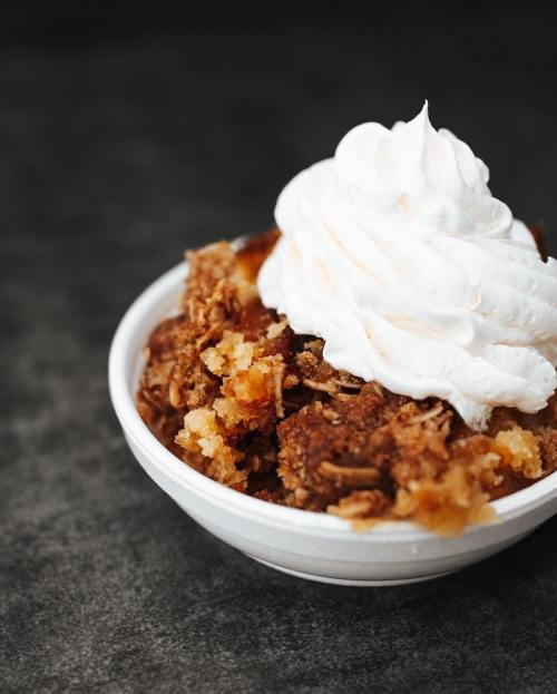A bowl of dessert featuring crumbled cake topped with a swirl of whipped cream.