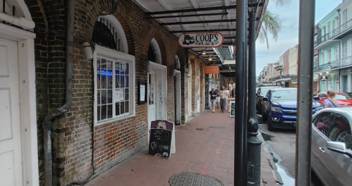 A bustling street scene featuring brick buildings, a restaurant sign, and people walking along the sidewalk.