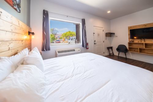 Cozy hotel room with a large bed, window view, TV, and minimalist decor.