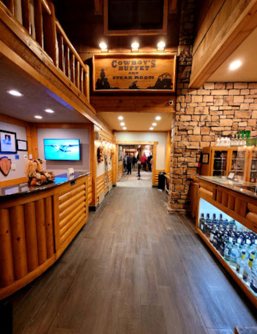 Interior of a rustic restaurant with wooden decor, a bar, and a hallway leading to dining areas.