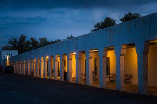 A dimly lit corridor of a rustic building with benches, under a cloudy evening sky.