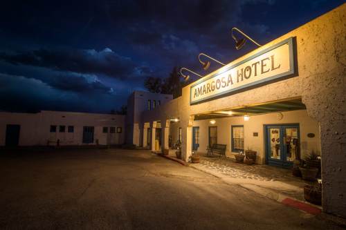 Amargosa Hotel entrance at dusk, illuminated under a dramatic sky with clouds.