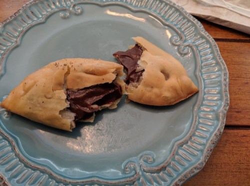 A blue plate holds two chocolate-filled pastries, one partially broken open to reveal the creamy filling inside.