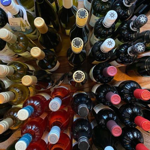 A variety of wine bottles arranged in a circular display, featuring red, white, and rosé options.